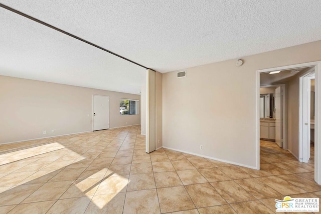 unfurnished room featuring light tile patterned floors and a textured ceiling