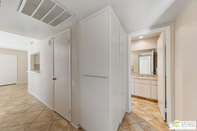 hallway featuring light tile patterned floors and sink