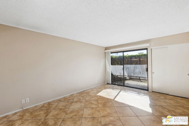 empty room featuring a textured ceiling and light tile patterned floors