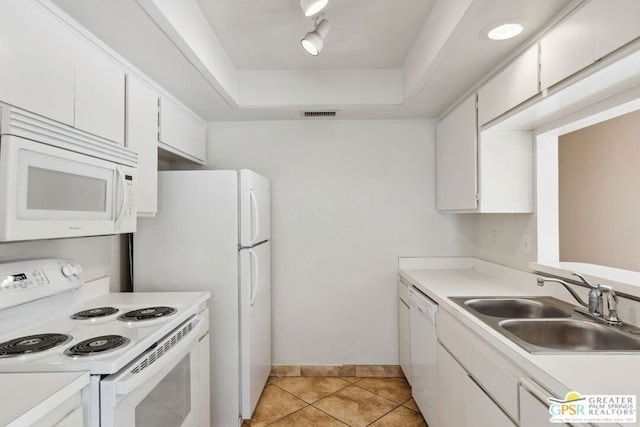 kitchen featuring a raised ceiling, white appliances, light tile patterned flooring, white cabinets, and sink