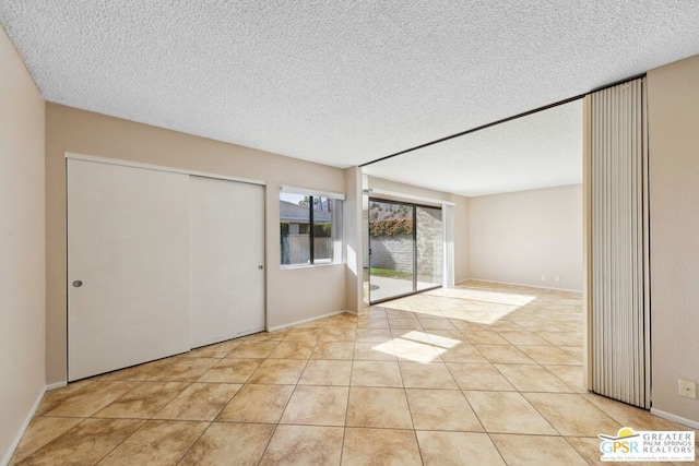 tiled empty room featuring a textured ceiling