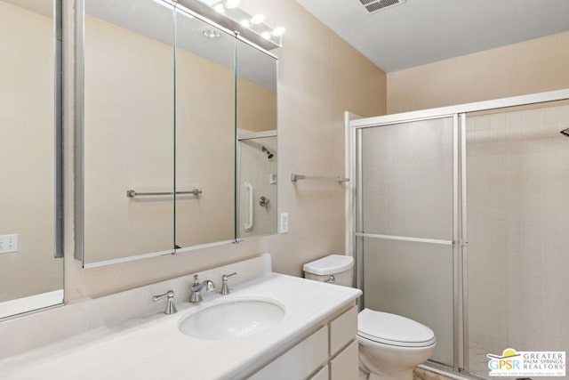 bathroom featuring toilet, a shower with shower door, and vanity