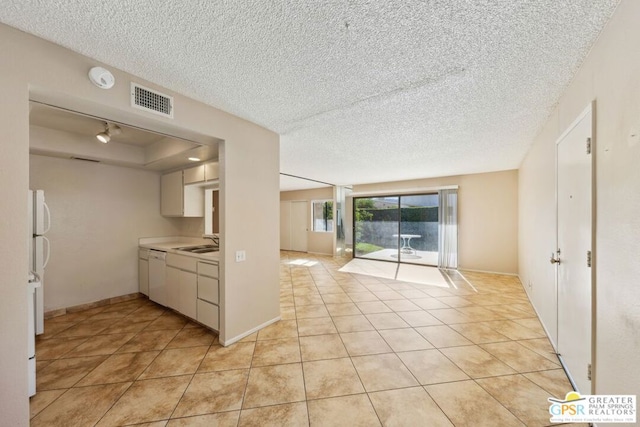 kitchen featuring white dishwasher, sink, a textured ceiling, and light tile patterned flooring