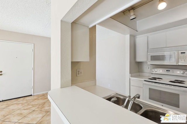 kitchen with light tile patterned floors, white cabinetry, white appliances, a textured ceiling, and sink