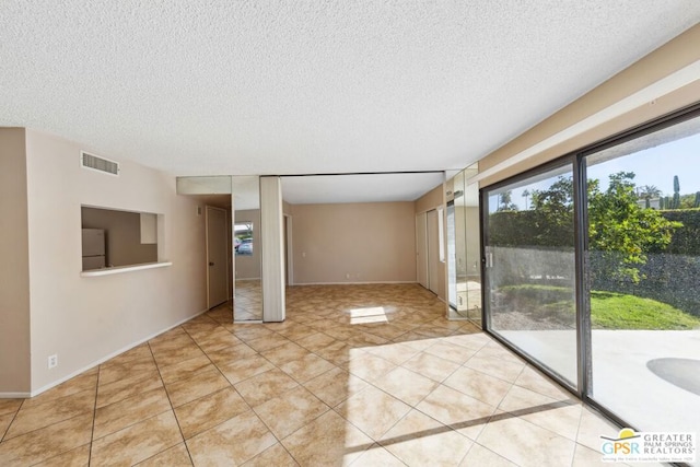 empty room with light tile patterned flooring and a textured ceiling