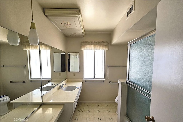 bathroom featuring toilet, vanity, and an enclosed shower