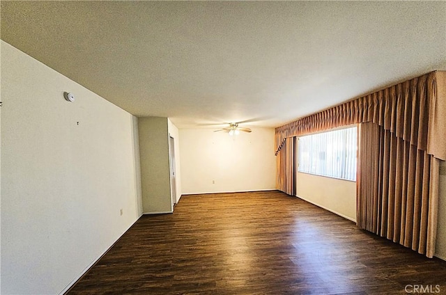 spare room with ceiling fan, a textured ceiling, and dark hardwood / wood-style flooring