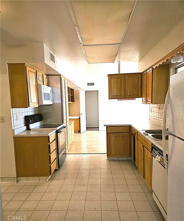 kitchen featuring white appliances, decorative backsplash, sink, kitchen peninsula, and light tile patterned floors