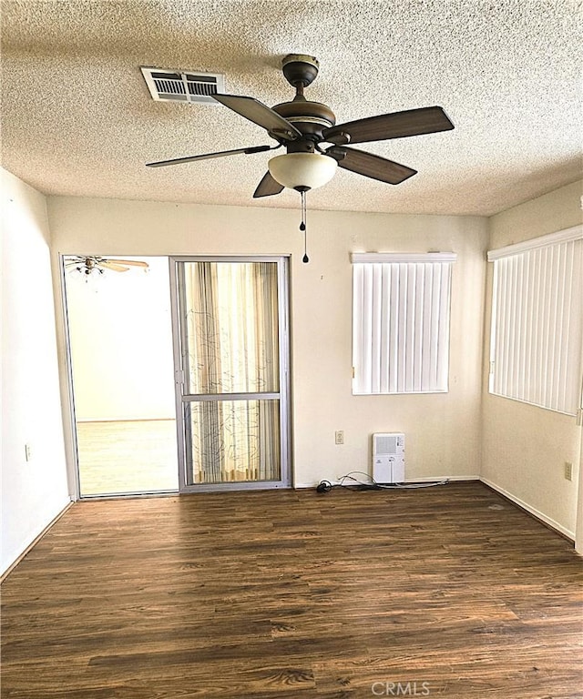 spare room with a textured ceiling and dark hardwood / wood-style flooring