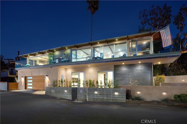 contemporary home featuring a balcony, a fenced front yard, and stucco siding