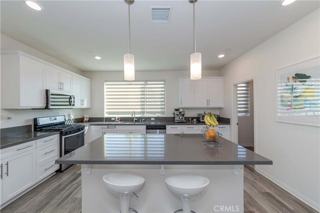 kitchen featuring appliances with stainless steel finishes, pendant lighting, white cabinetry, and a center island