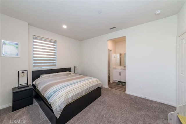 bedroom featuring ensuite bathroom and light colored carpet