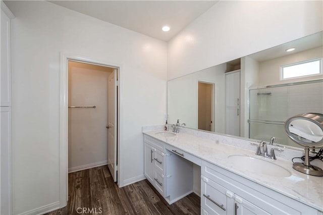 bathroom with a shower with shower door, hardwood / wood-style floors, and vanity