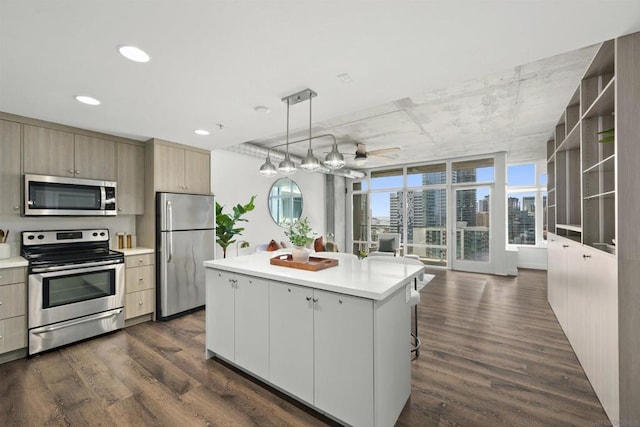 kitchen featuring ceiling fan, dark hardwood / wood-style floors, a center island, hanging light fixtures, and stainless steel appliances