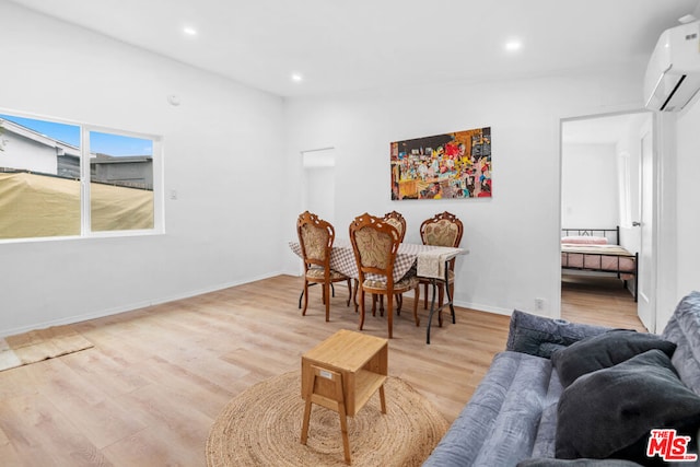 sitting room with an AC wall unit, vaulted ceiling, and light wood-type flooring