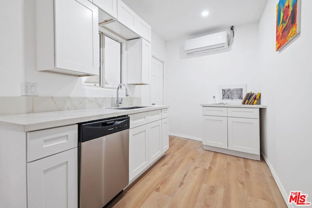 kitchen featuring an AC wall unit, light hardwood / wood-style floors, stainless steel dishwasher, sink, and white cabinets