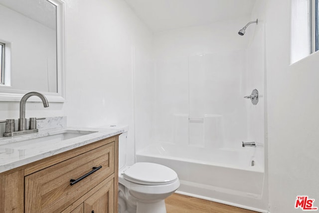 full bathroom featuring toilet, hardwood / wood-style floors, a healthy amount of sunlight,  shower combination, and vanity