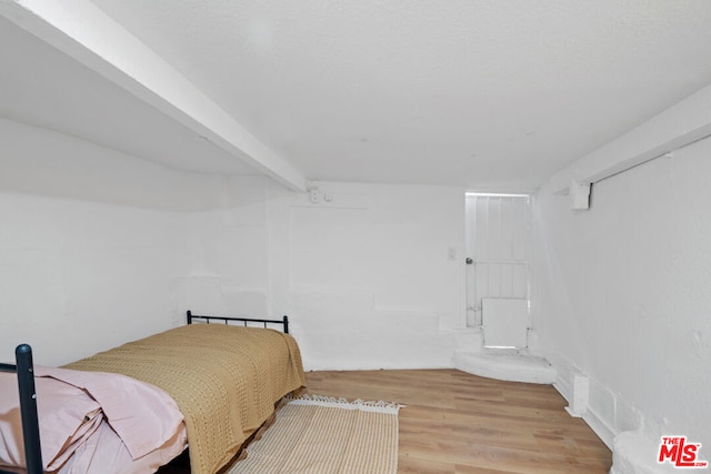 bedroom featuring beam ceiling and hardwood / wood-style flooring