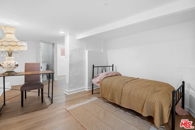 bedroom featuring beamed ceiling and light hardwood / wood-style floors