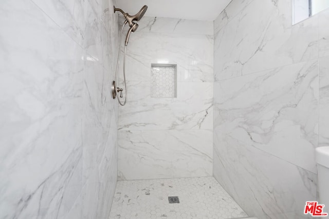 bathroom featuring toilet and a tile shower