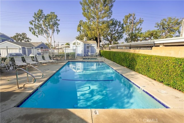 view of pool featuring a patio and a shed