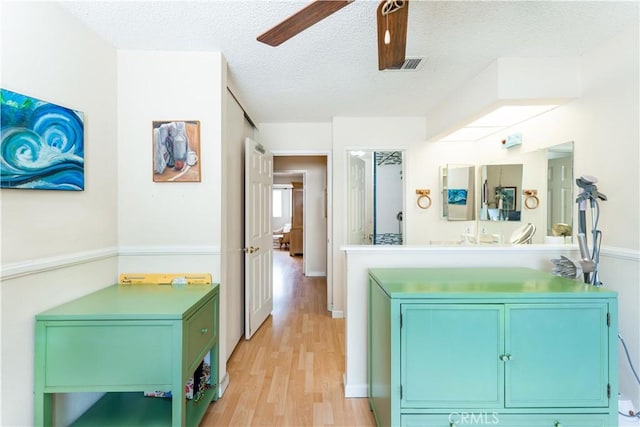 kitchen with a textured ceiling, ceiling fan, and light hardwood / wood-style floors