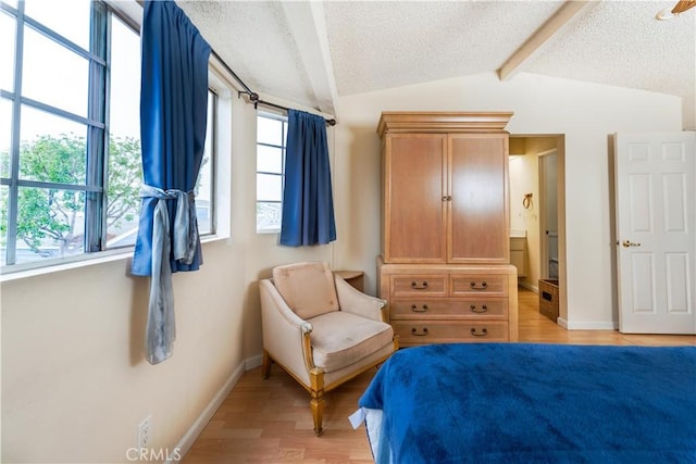 bedroom featuring a textured ceiling, vaulted ceiling with beams, and light hardwood / wood-style flooring