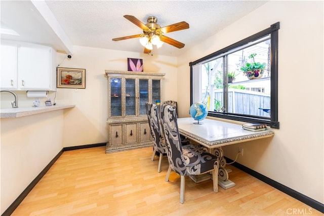 dining room with light hardwood / wood-style floors, sink, a textured ceiling, and ceiling fan