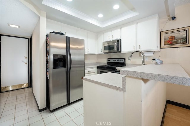 kitchen with white cabinetry, kitchen peninsula, a tray ceiling, and stainless steel appliances