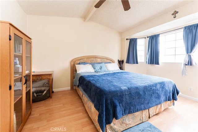 bedroom featuring ceiling fan, a textured ceiling, light hardwood / wood-style flooring, and lofted ceiling with beams