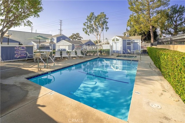 view of swimming pool with a storage shed and a patio