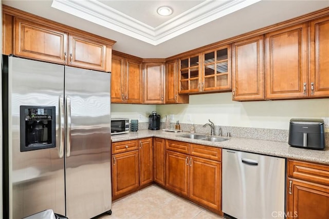 kitchen with sink, a tray ceiling, appliances with stainless steel finishes, ornamental molding, and light tile patterned floors