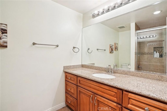 bathroom featuring toilet, a shower with shower door, and vanity