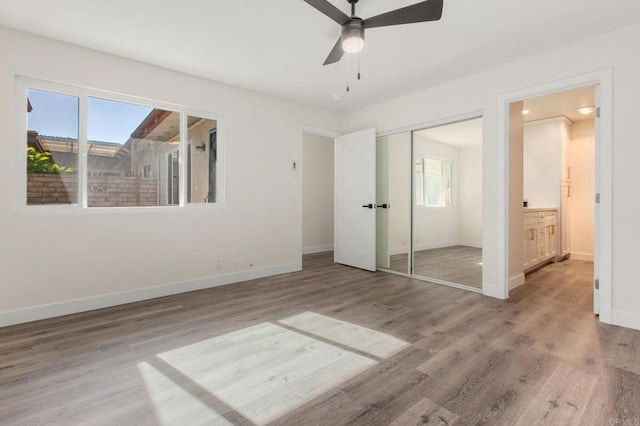 unfurnished bedroom with multiple windows, wood-type flooring, a closet, and ceiling fan