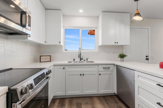 kitchen with sink, stainless steel appliances, dark hardwood / wood-style floors, pendant lighting, and white cabinets