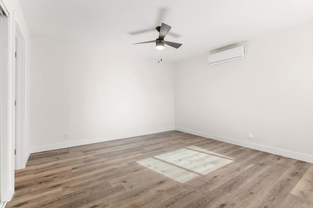 empty room with a wall mounted air conditioner, ceiling fan, and hardwood / wood-style floors