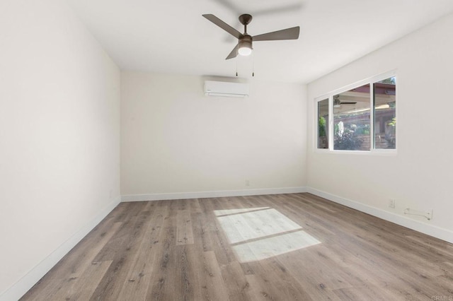 empty room featuring ceiling fan, light hardwood / wood-style floors, and a wall mounted air conditioner