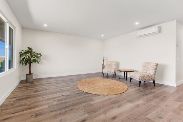 sitting room with hardwood / wood-style floors and an AC wall unit