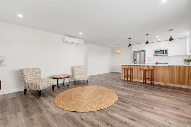 living area with light hardwood / wood-style floors and an AC wall unit