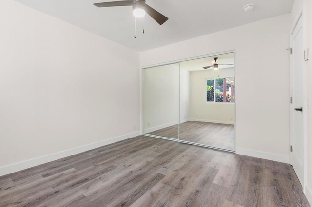 unfurnished bedroom featuring ceiling fan, a closet, and hardwood / wood-style floors