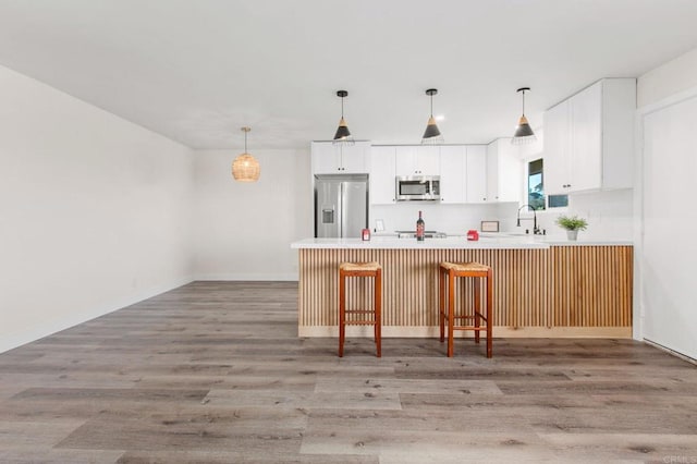 kitchen featuring white cabinets, a kitchen breakfast bar, sink, light hardwood / wood-style floors, and stainless steel appliances