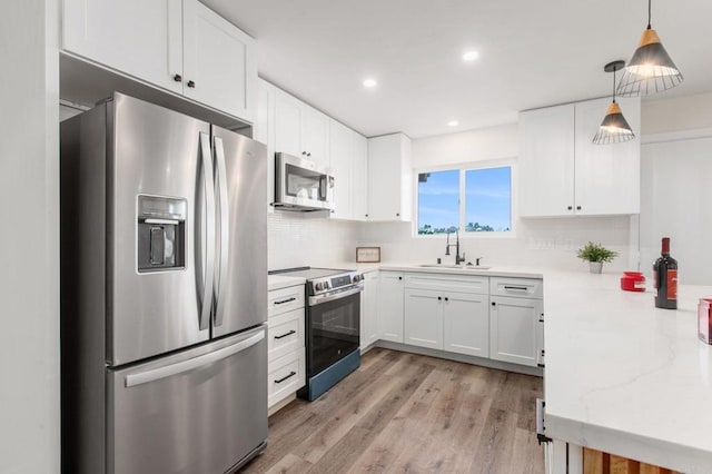 kitchen with white cabinetry, sink, stainless steel appliances, tasteful backsplash, and decorative light fixtures