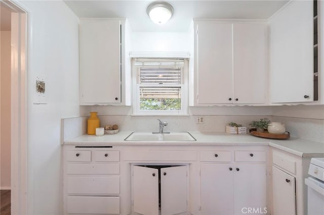 kitchen featuring stove, white cabinetry, and sink