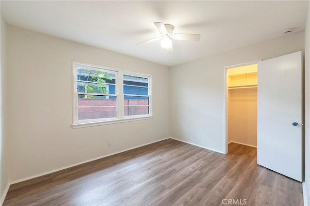 unfurnished bedroom featuring ceiling fan, a spacious closet, a closet, and light hardwood / wood-style flooring