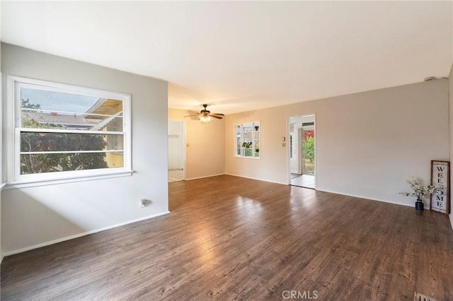 empty room with ceiling fan, dark hardwood / wood-style floors, and a healthy amount of sunlight