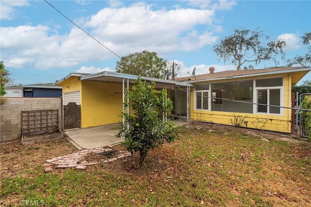 rear view of property featuring a sunroom and a yard