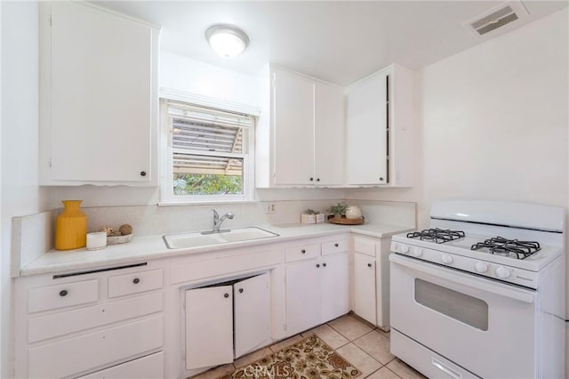 kitchen featuring light tile patterned floors, sink, white cabinets, and white gas range oven