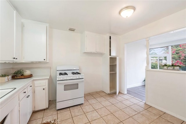 kitchen featuring light tile patterned floors, white cabinetry, and white gas range oven