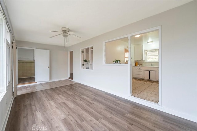 unfurnished room with light hardwood / wood-style floors, sink, and ceiling fan