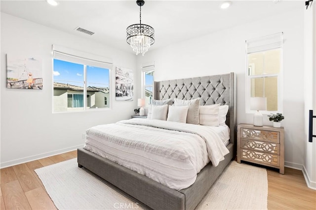 bedroom with light hardwood / wood-style flooring and a notable chandelier